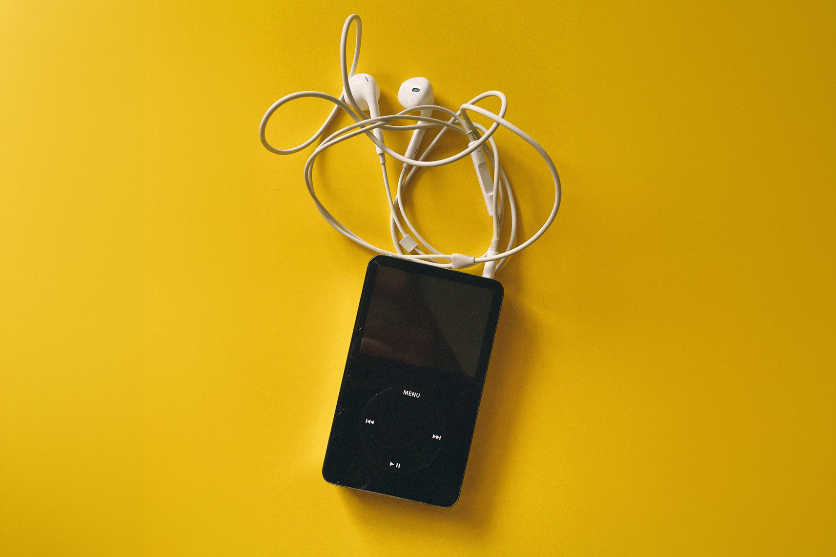 iPod with earbuds on yellow background